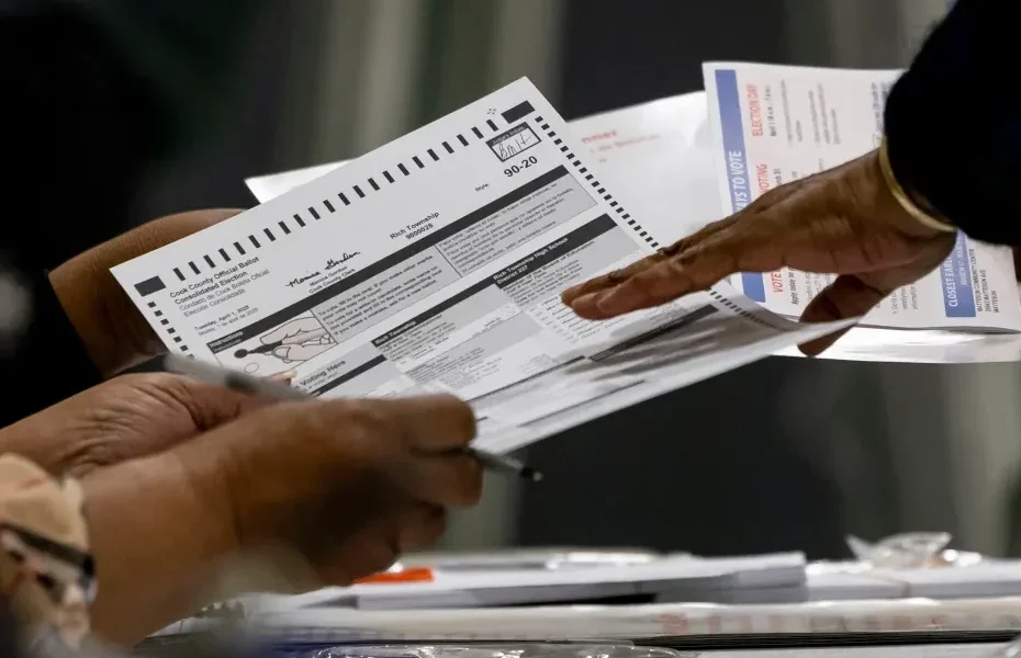 A voter receives a ballot on April 1, 2025, in the suburban Cook County Consolidated Election at Yates Elementary School in Matteson